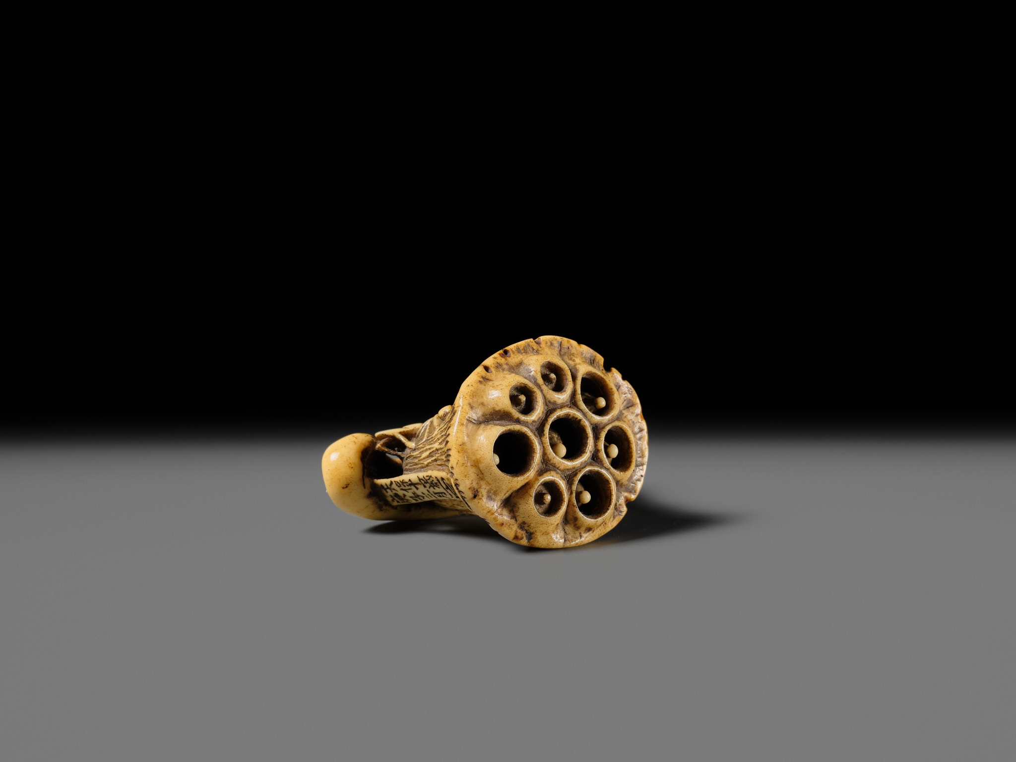 Artwork by Hizen Matsura Ittei, ITTEI: AN ANTLER (TRICK) NETSUKE OF A LOTUS POD WITH THE MAKINO CLAN MON, Made of plaque