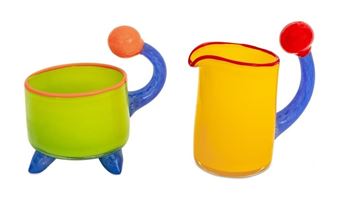 A whimsical ceramic set featuring a green cup and yellow pitcher with alien-like handles.