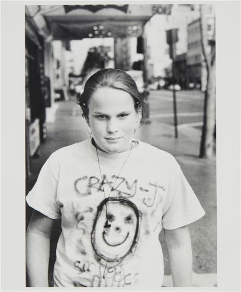 A black-and-white portrait of a person wearing a t-shirt with a hand-drawn smiley face and text.