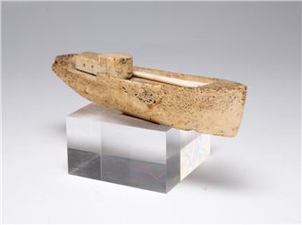 A small boat sculpture resting on a clear acrylic block.