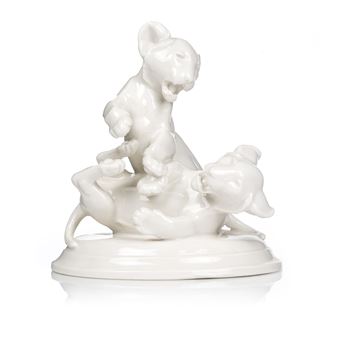 A glossy white ceramic sculpture of a small animal standing triumphantly over another figure.