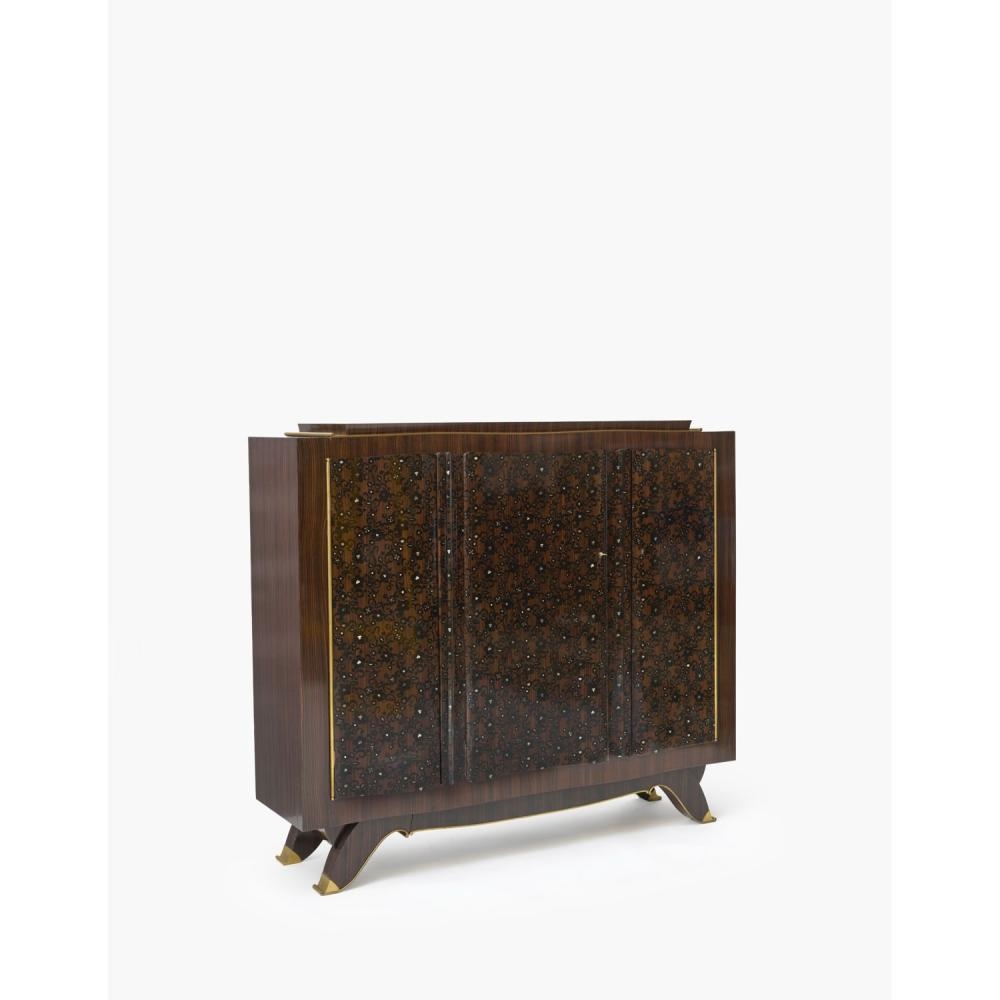 Artwork by Jules Leleu, gilt bronze edging, Made of Important meuble à hauteur d’appui en ébène de Macassar, ouvrant à trois portes ornées d’un riche décor de rinceaux fleuris en marqueterie d’ébène et de nacre ; plateau supérieur à gradins, portes et piétement soulignés de baguettes en bronze doré ; pieds à réception de sabots en bronze
