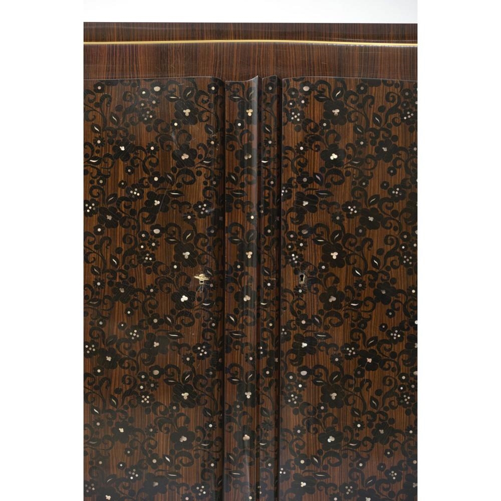 Artwork by Jules Leleu, gilt bronze edging, Made of Important meuble à hauteur d’appui en ébène de Macassar, ouvrant à trois portes ornées d’un riche décor de rinceaux fleuris en marqueterie d’ébène et de nacre ; plateau supérieur à gradins, portes et piétement soulignés de baguettes en bronze doré ; pieds à réception de sabots en bronze
