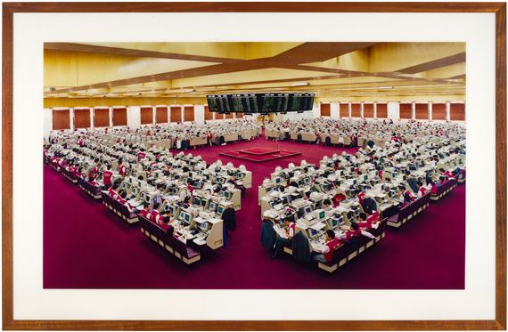 A high-angle view of a massive conference hall filled with rows of computer workstations.