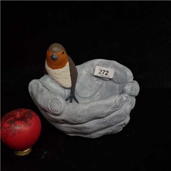 A very heavy decorative stone bird bath sculpture featuring a hand painted robin perched within two cupped hands.