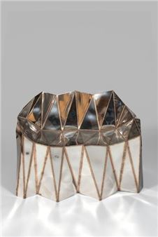 A metallic geometric vase with a faceted, diamond-like structure.