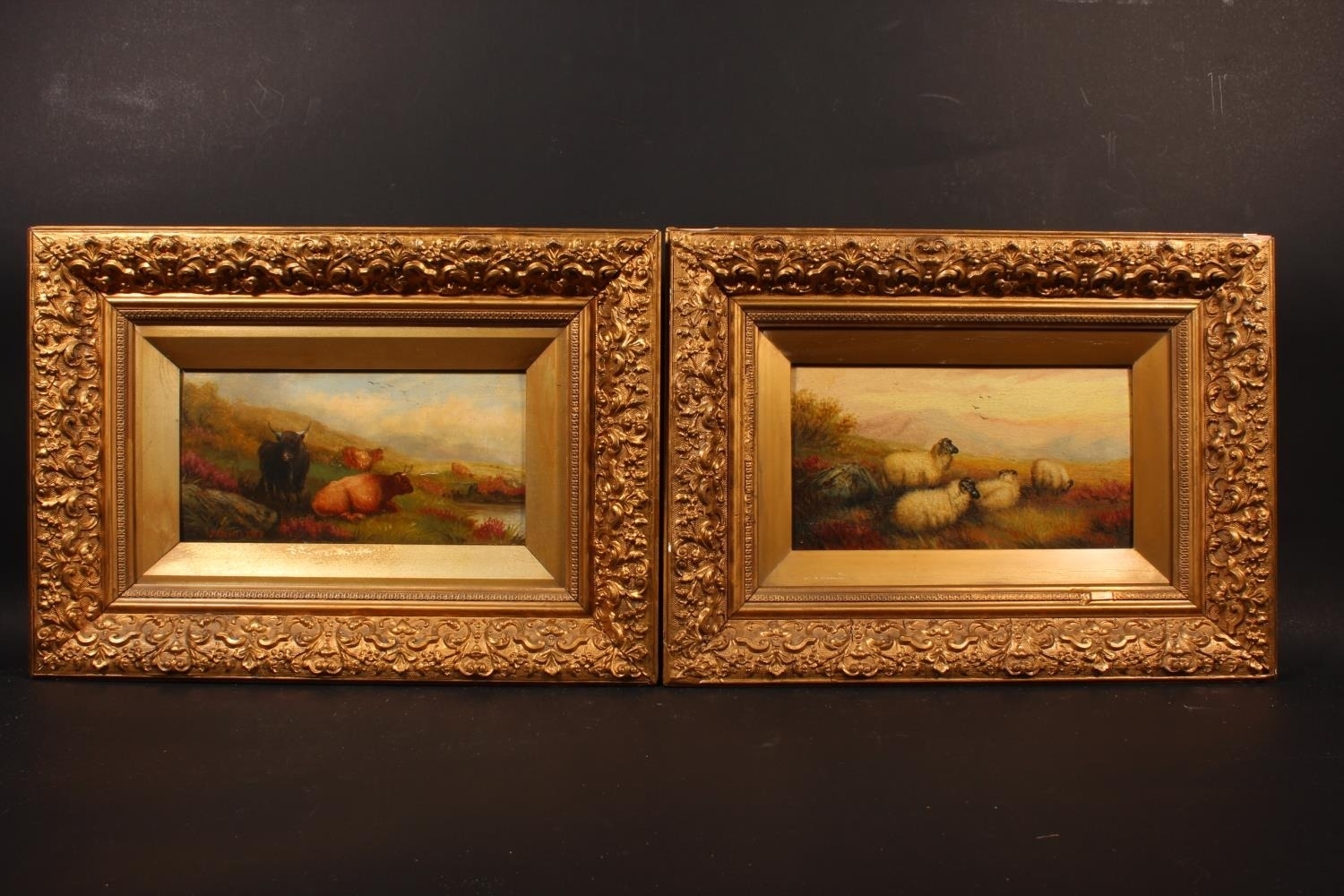 A pair of ornate gold-framed pastoral paintings depicting rural scenes with animals.