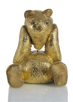 A golden, textured bear figurine posed with hands on its cheeks.