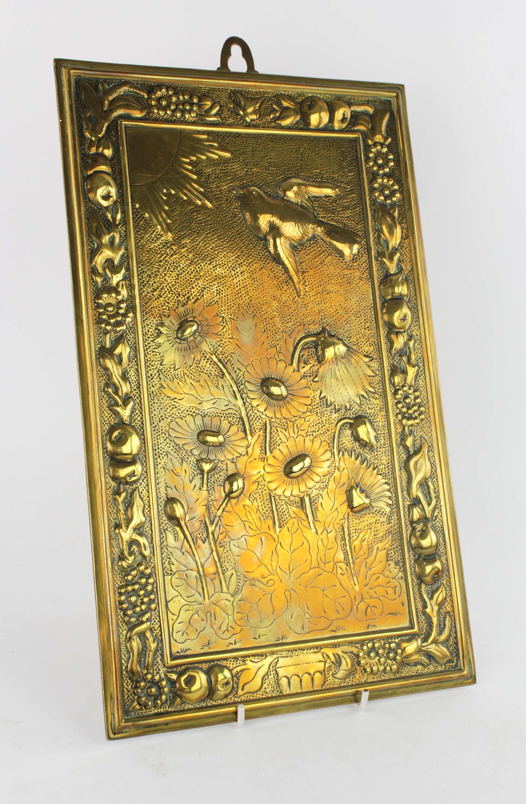 Artwork by Bruce Talbert, MANNER OF BRUCE TALBERT, a rectangular brass plaque, decorated with a bird flying towards the sun, above lotus plants, in a border of fruit and flowers, 38 x 23cm, Made of brass plaque