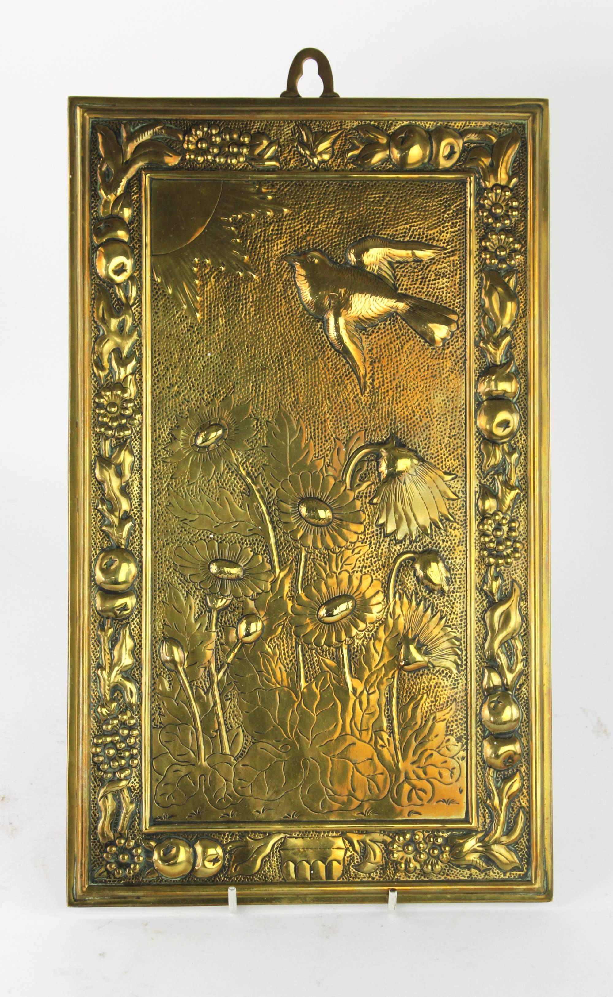 Artwork by Bruce Talbert, MANNER OF BRUCE TALBERT, a rectangular brass plaque, decorated with a bird flying towards the sun, above lotus plants, in a border of fruit and flowers, 38 x 23cm, Made of brass plaque