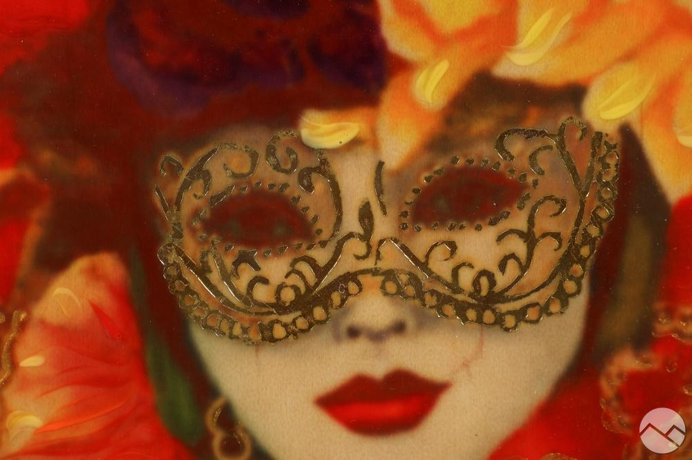 A masked figure in a richly ornate frame adorned with floral and geometric patterns.