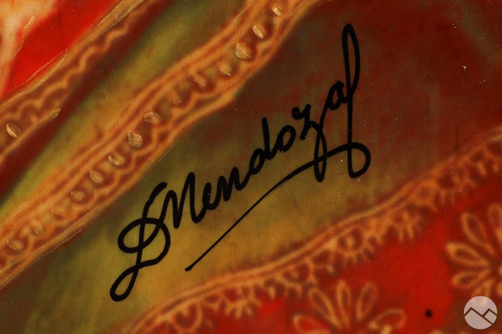 A masked figure in a richly ornate frame adorned with floral and geometric patterns.