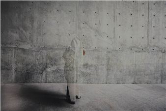 A person standing in front of a concrete wall.
