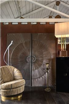 A modern interior scene featuring a textured armchair and ornate double doors.