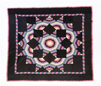 A colorful quilt featuring a geometric starburst pattern on a black background.