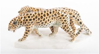 A ceramic sculpture of two spotted leopards in mid-stride.