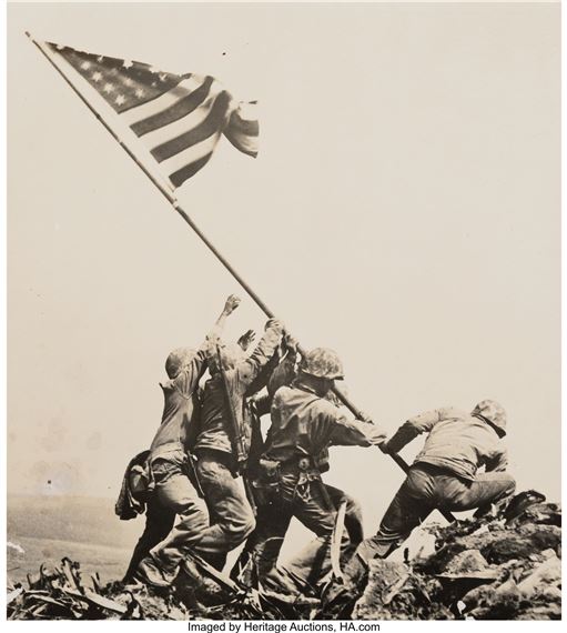 A group of men raising a flag on top of a mountain.