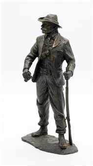 A bronze sculpture of a walking figure in a hat and suit.
