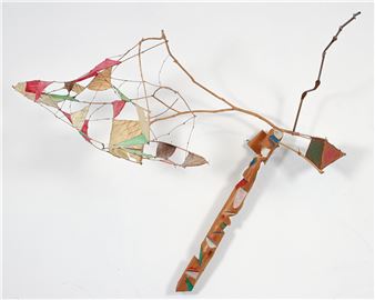 A sculptural assemblage featuring a long, segmented stick with a net-like structure and colorful triangular elements.