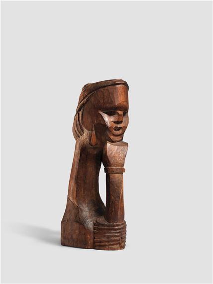 A wooden sculpture of a seated figure with stylized features and a draped headpiece.