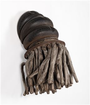 A sculptural object resembling a dark, bulbous head with numerous textured tendrils hanging from its base.