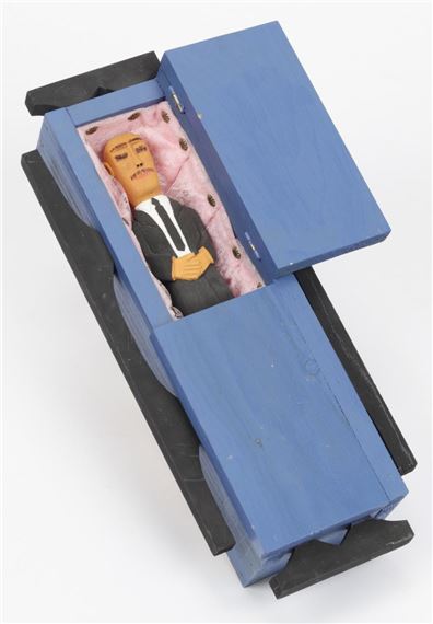 A miniature coffin containing a tiny figure dressed in formal attire.
