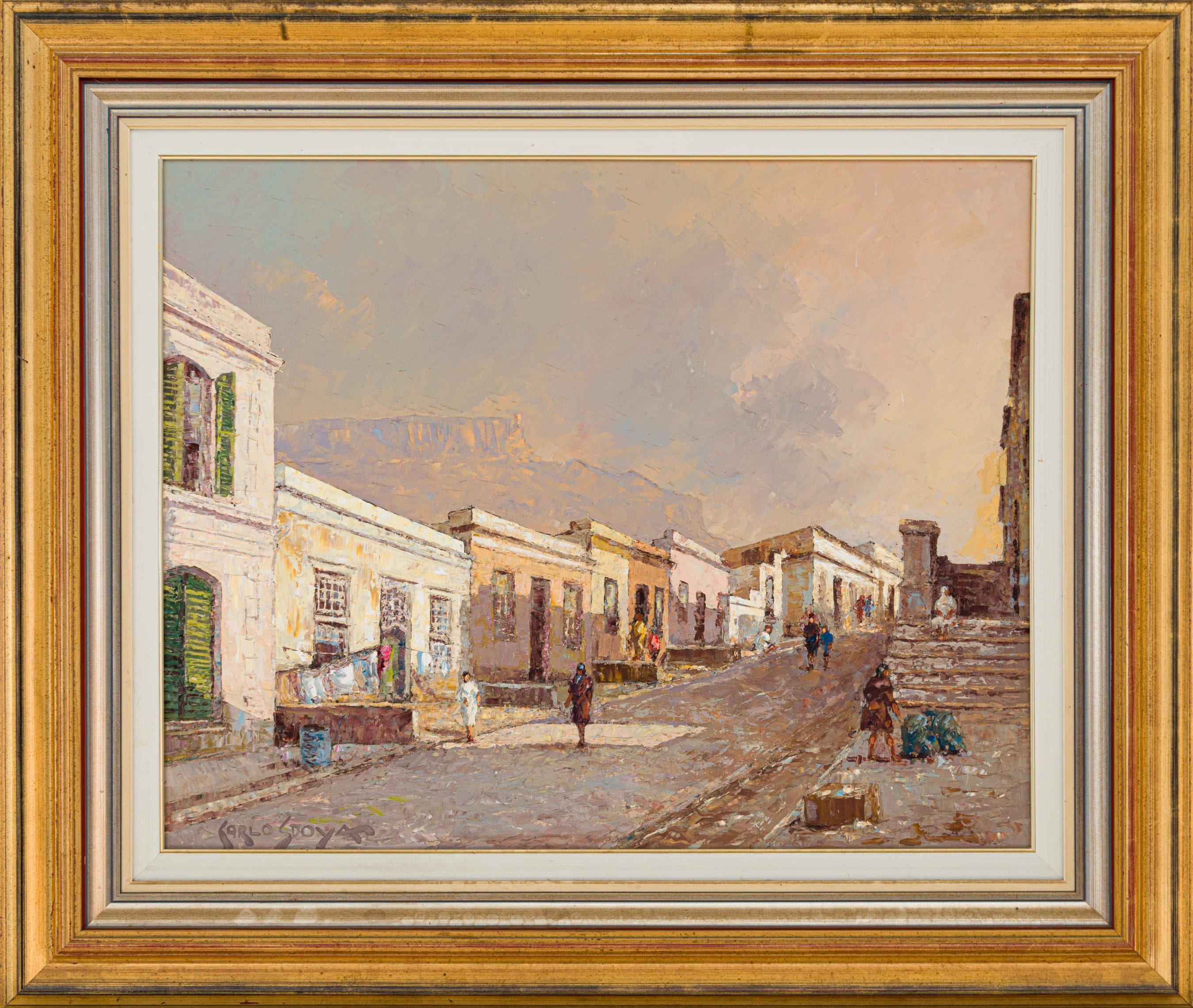 A sun-drenched street scene with colonial-style buildings and distant mountains.