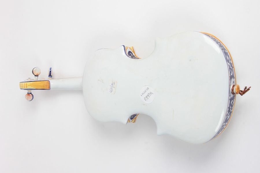 Artwork by Henriot Quimper, Earthenware violin with polychrome decoration depicting Bretons playing boule bretonne, Made of Earthenware