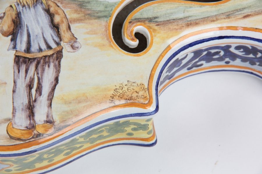 Artwork by Henriot Quimper, Earthenware violin with polychrome decoration depicting Bretons playing boule bretonne, Made of Earthenware