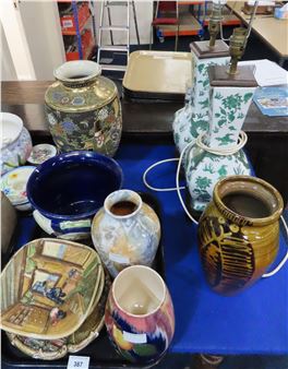 A colorful assortment of ceramic vases and lamps arranged on a blue surface.