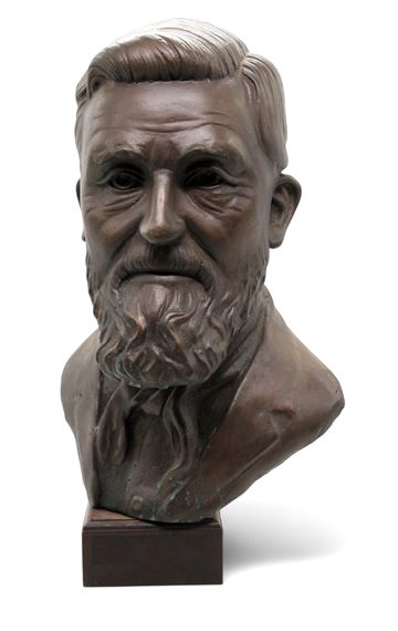 A bronze bust of a bearded man with a solemn expression, mounted on a dark rectangular base.