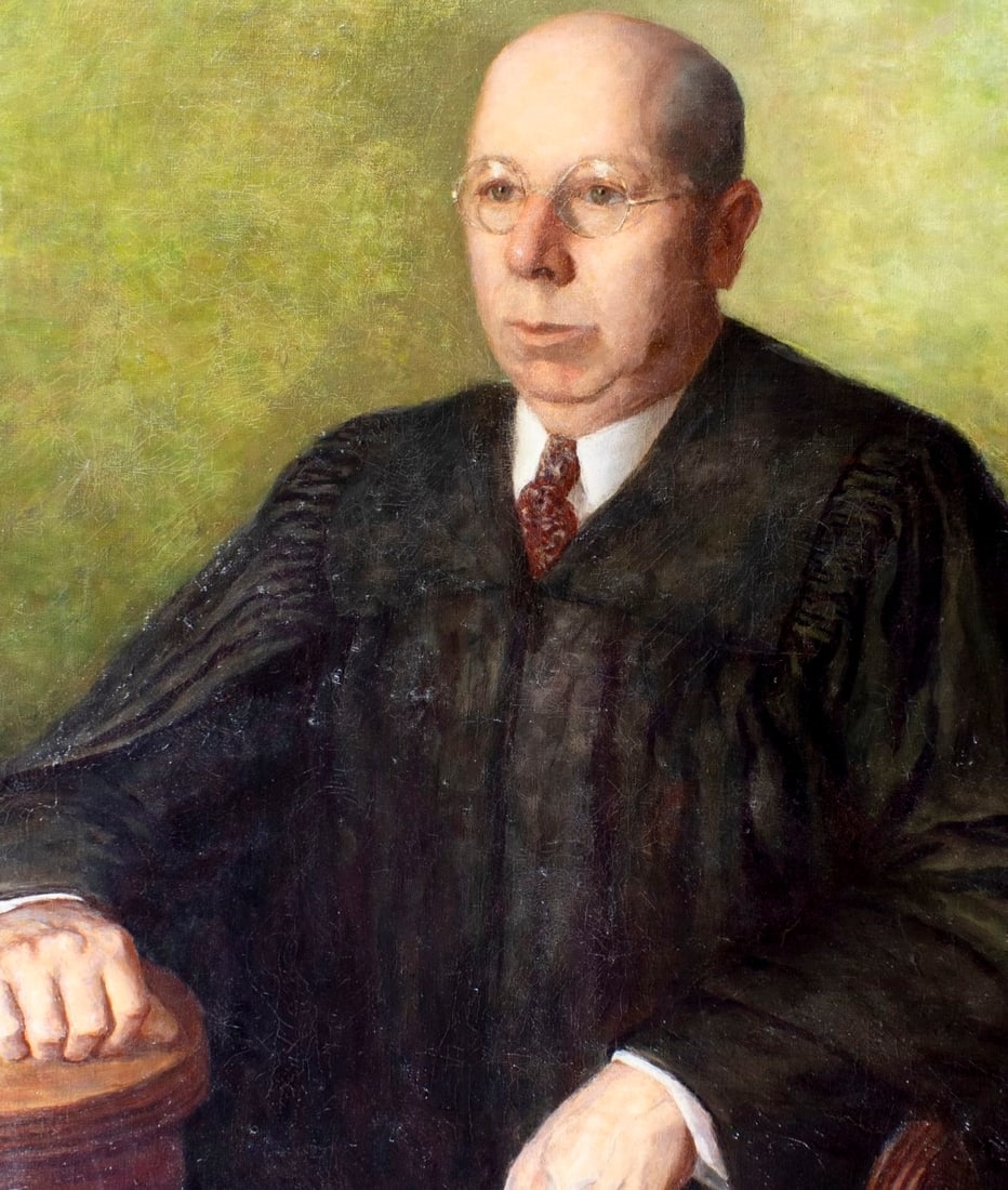 A formal portrait of a seated figure in judicial robes against a muted green background.