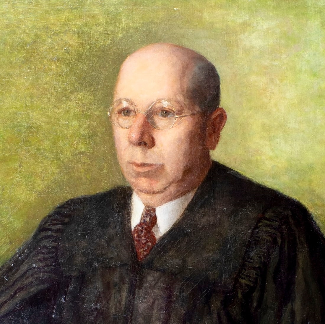 A formal portrait of a seated figure in judicial robes against a muted green background.