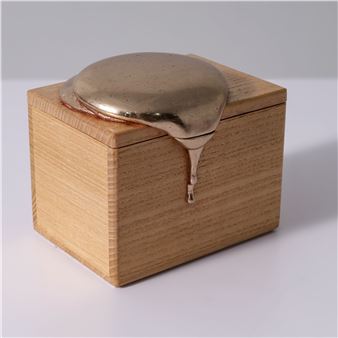 A wooden box with a metallic lid that appears to be melting.