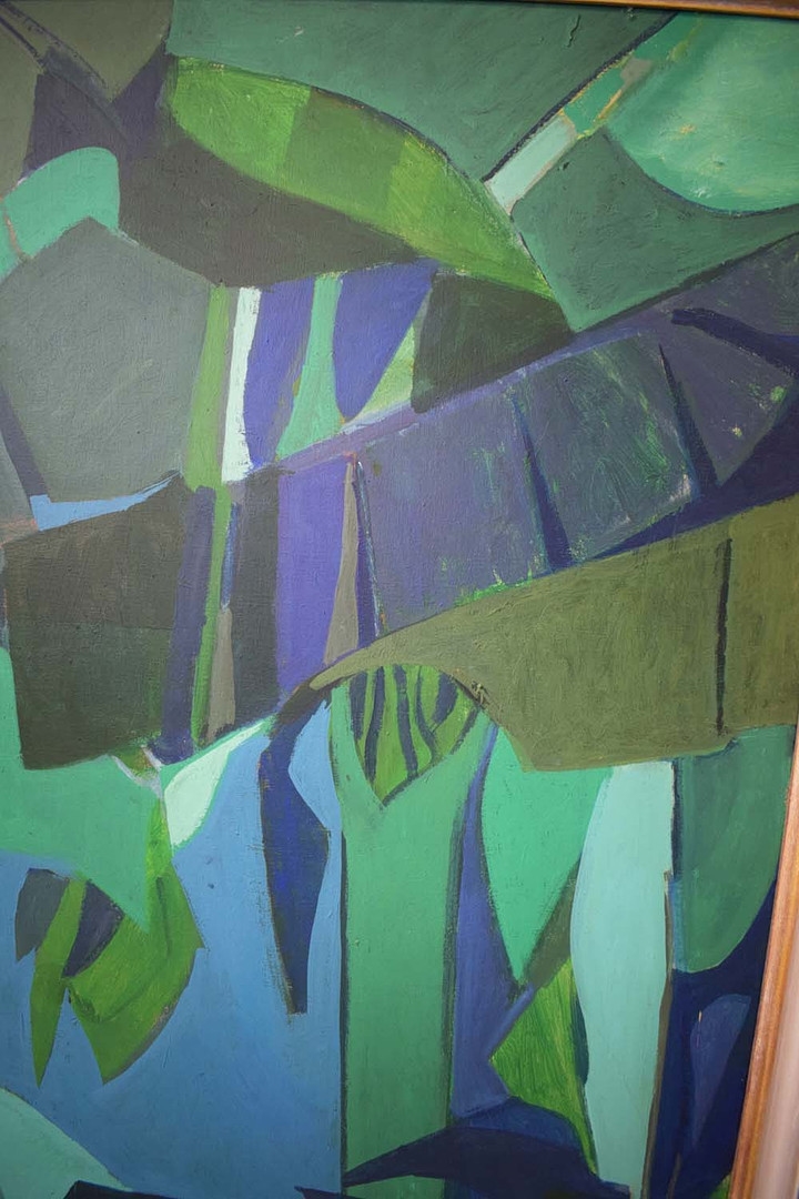 A geometric green and blue painting of a tropical plant in a dark frame.