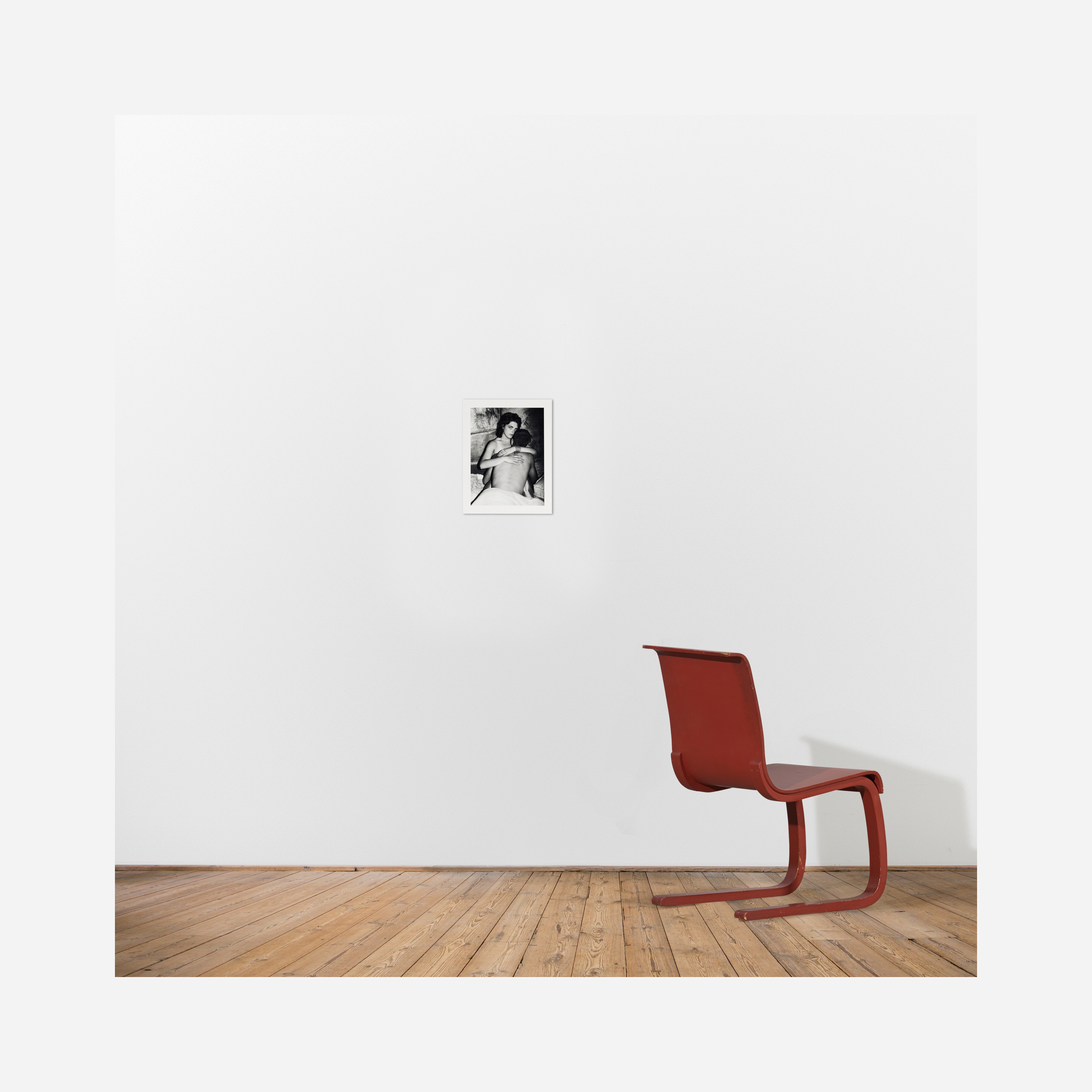 A black and white photograph of a woman embracing a man from behind, with her face turned toward the camera.