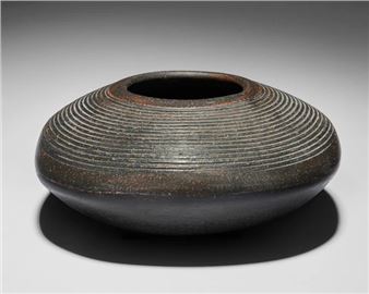 Vessel of squat form with combed decoration raised on four feet