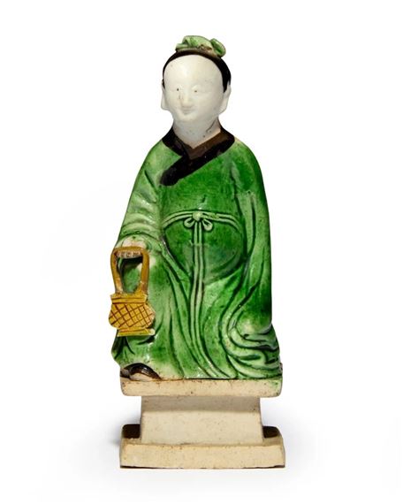 A Chinese famille verte biscuit figure of a young man holding a basket by Chinese School, Qing dynasty, Kangxi period