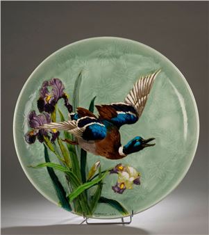 A plate with a painting of a duck flying over a flower.
