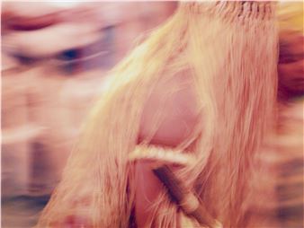 A motion-blurred portrait of a figure with long, light-colored hair and a braided accessory.