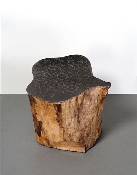 A wooden stool with a black top on a gray surface.