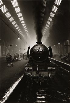 A black and white photo of a train in a train station.
