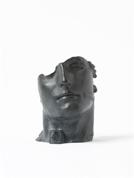A dark, abstract sculpture of a head with a fragmented face and smooth, rounded forms.