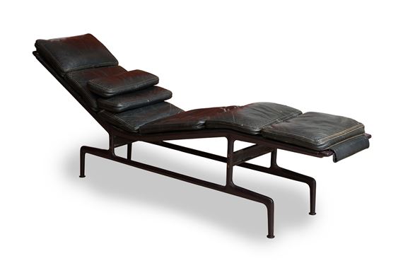 A mid-century modern lounge chair with dark leather cushions and a metal frame.