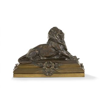 A bronze sculpture of a lion laying down on a marble base.