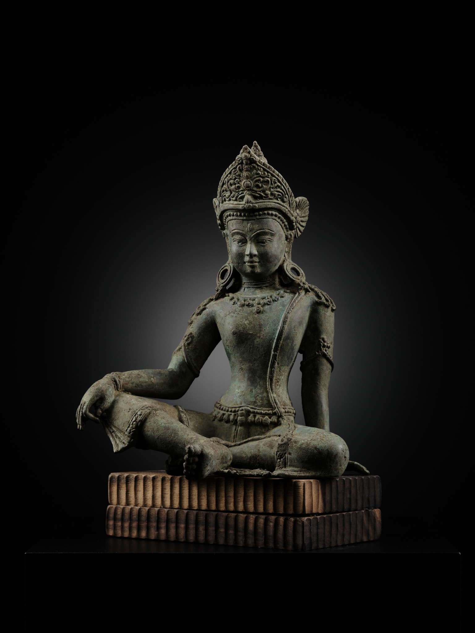 A statue of a seated buddha sitting on a wooden block.