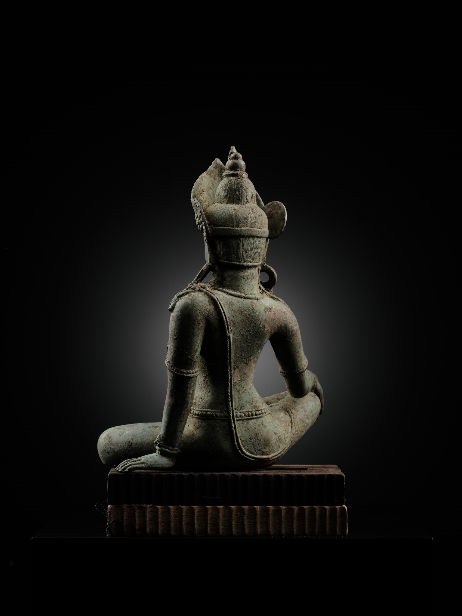 A statue of a seated buddha sitting on a wooden block.