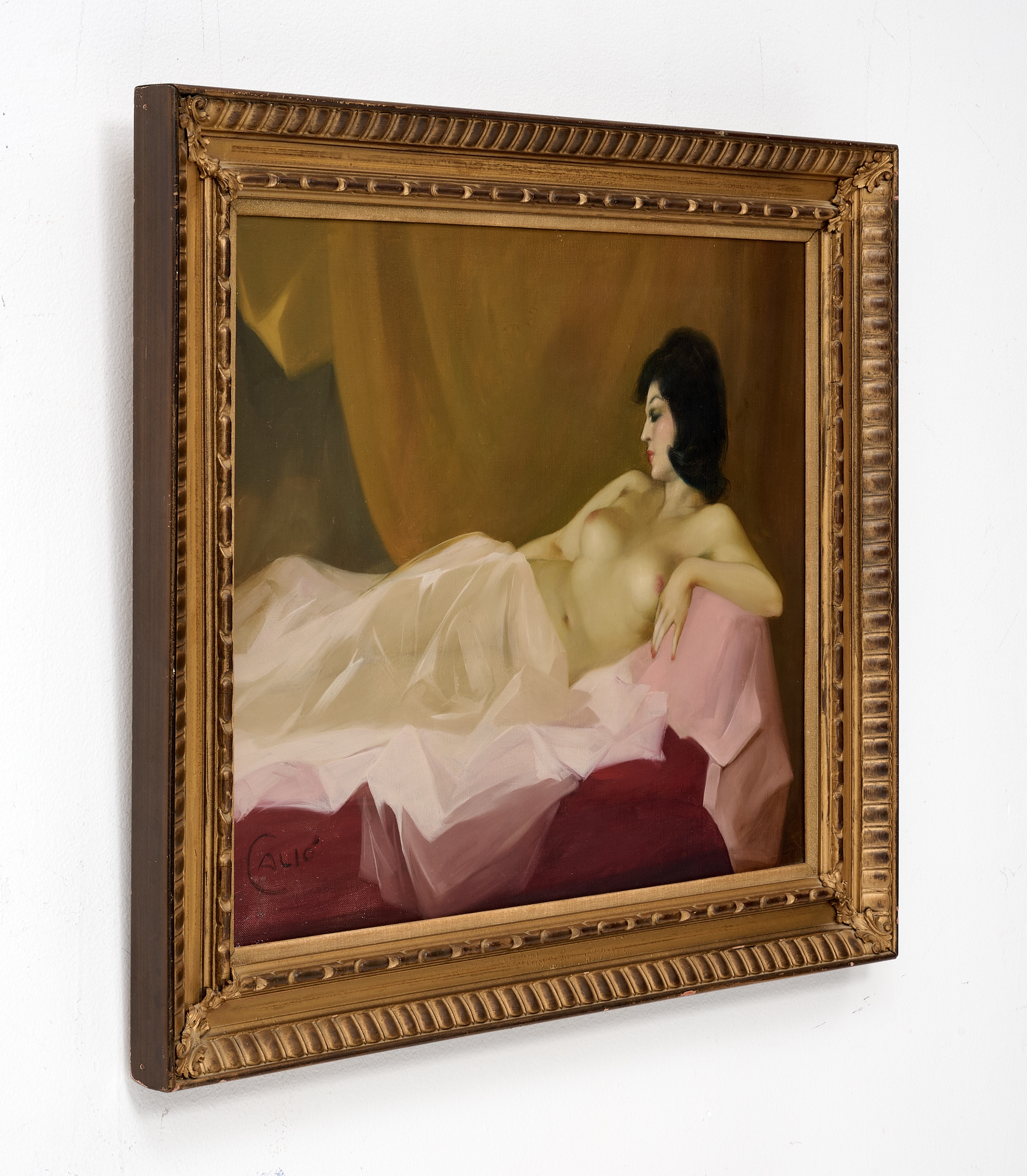 A classical oil painting of a reclining nude figure in a bed, framed in ornate gold.