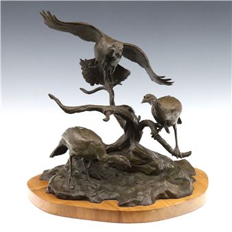 A bronze sculpture of three birds perched on a gnarled branch atop a wooden base.