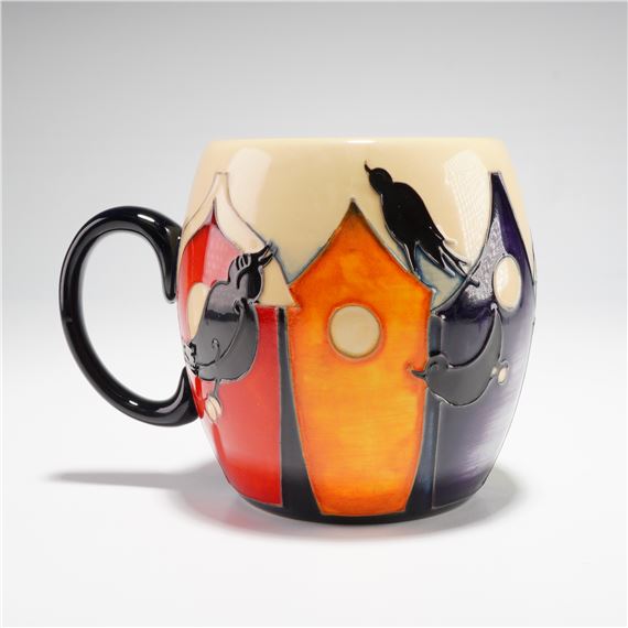 A ceramic mug featuring a stylized birdhouse design with bold colors and silhouetted birds.